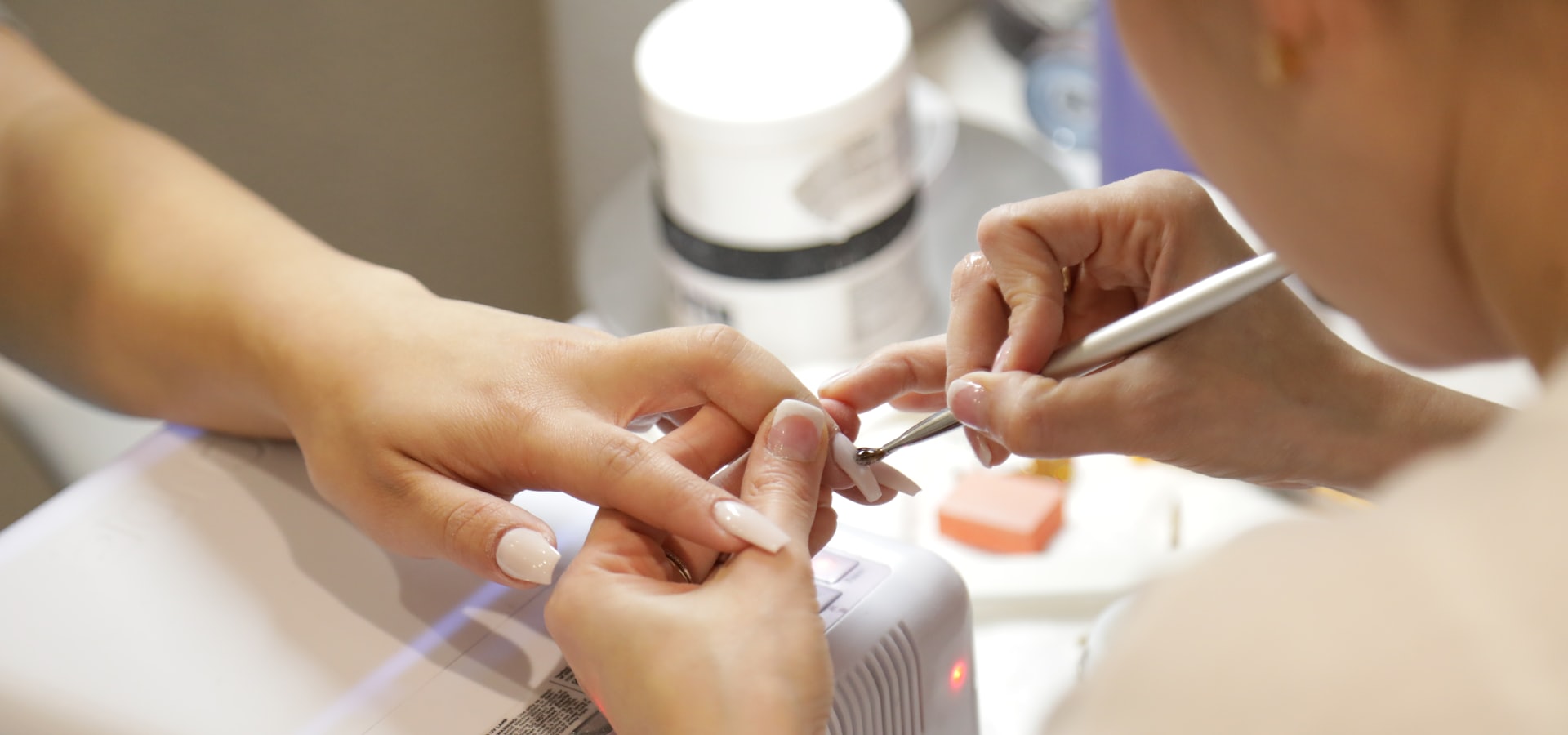 A nail technician shaping a client's nails at the studio table