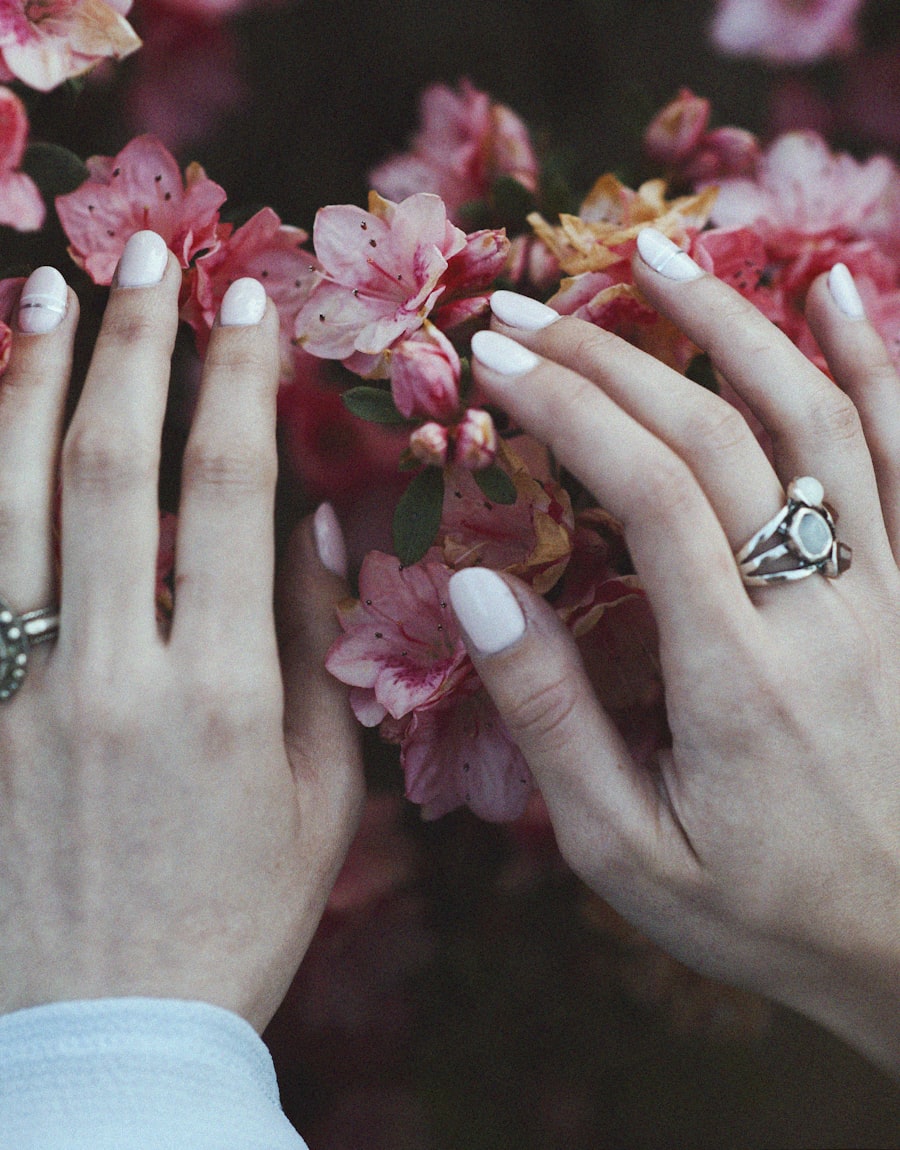 White manicure held among pink blossom branches