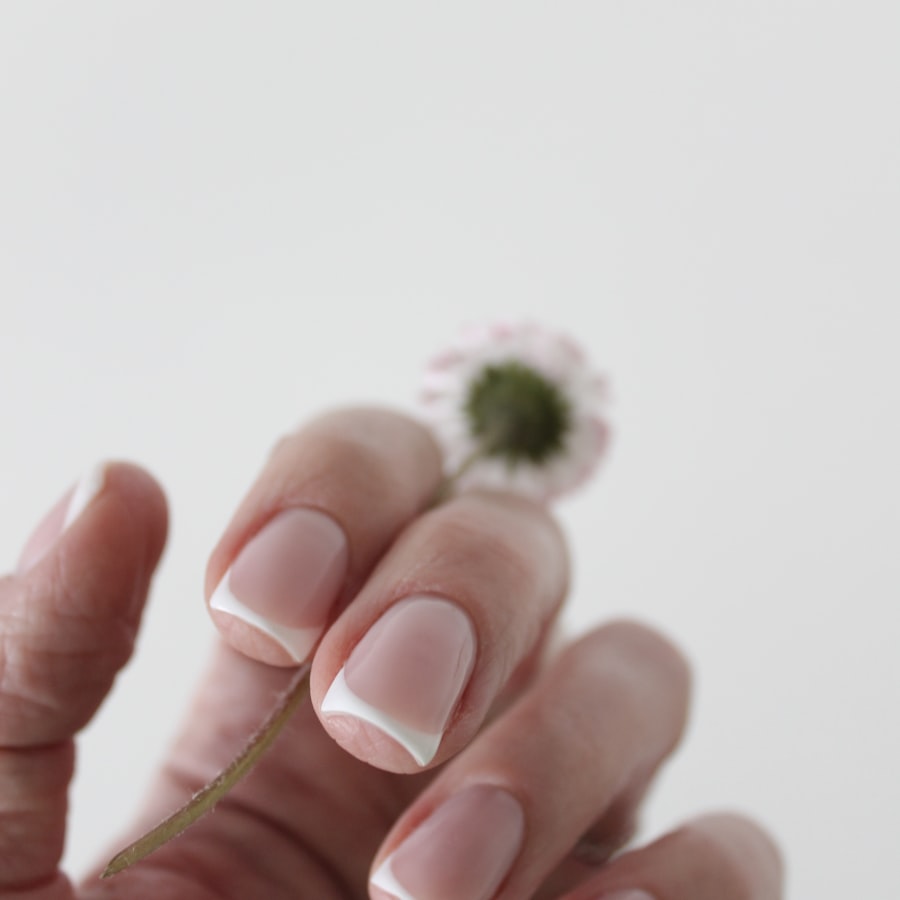 Natural French manicure pinching a tiny wildflower stem