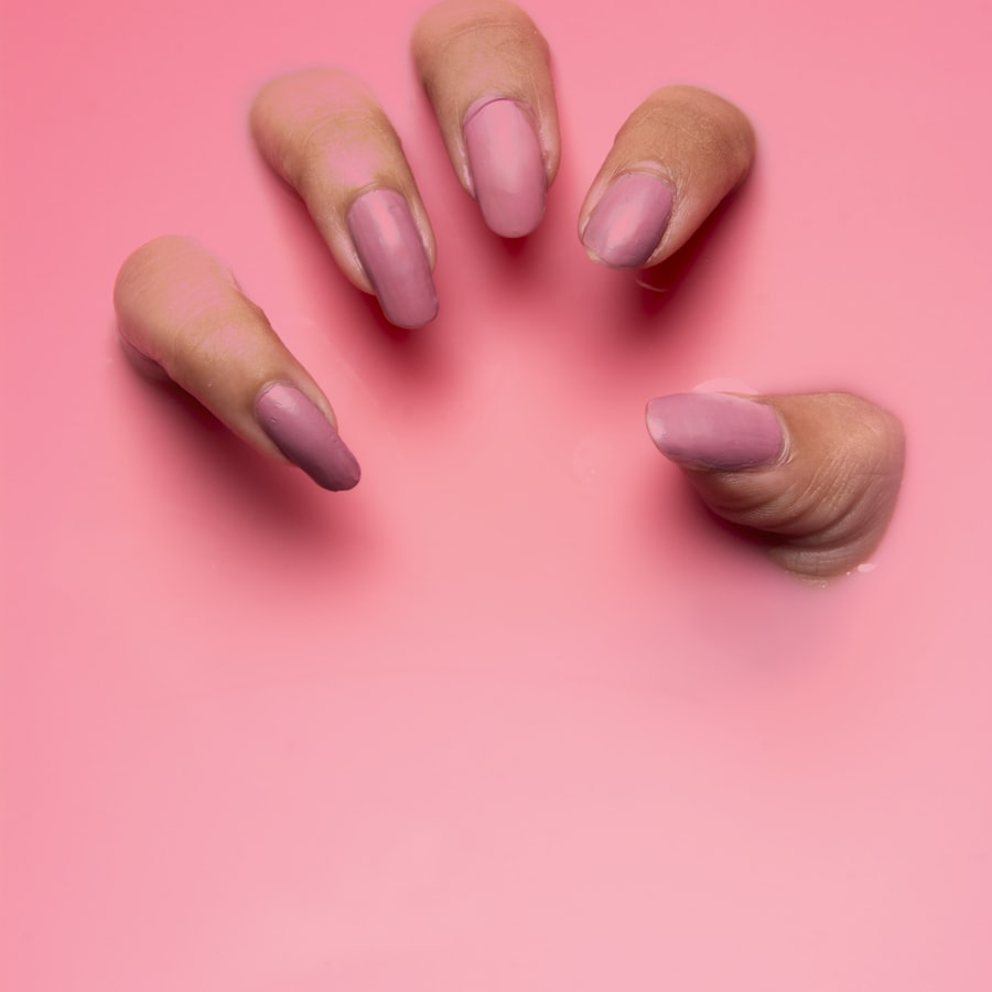 Mauve almond nails photographed on a rose-pink background