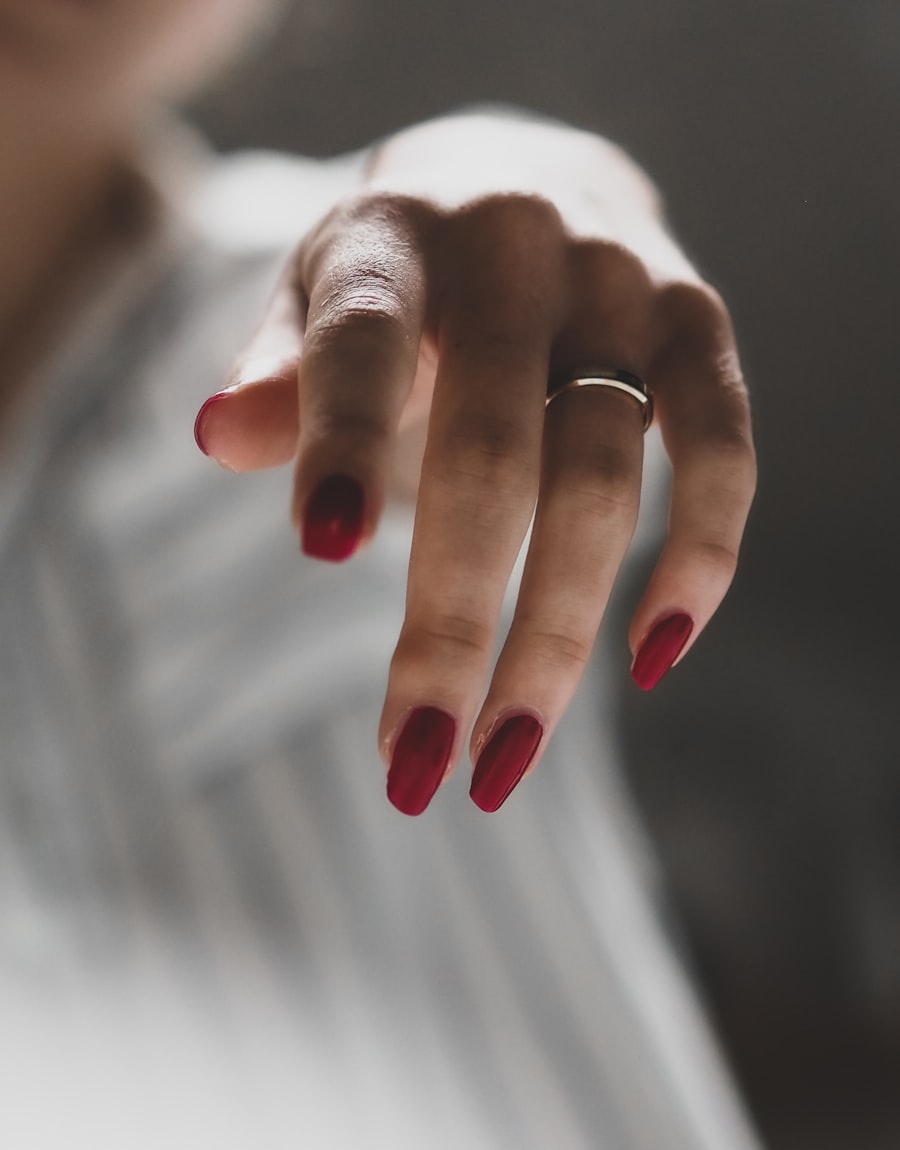 Oxblood red nails on a poised hand in soft light