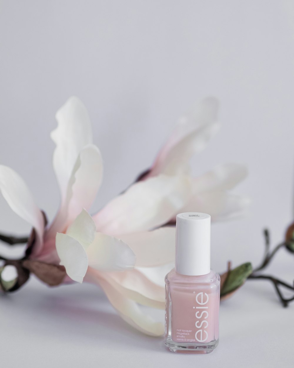 Magnolia blossom beside a bottle of blush nail polish