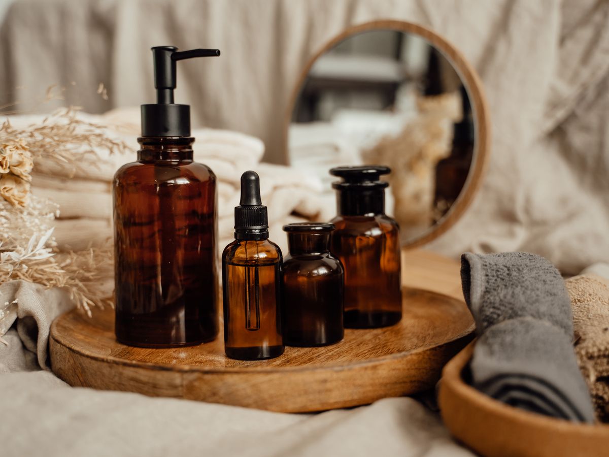 Amber apothecary bottles on a wooden tray beside folded linen