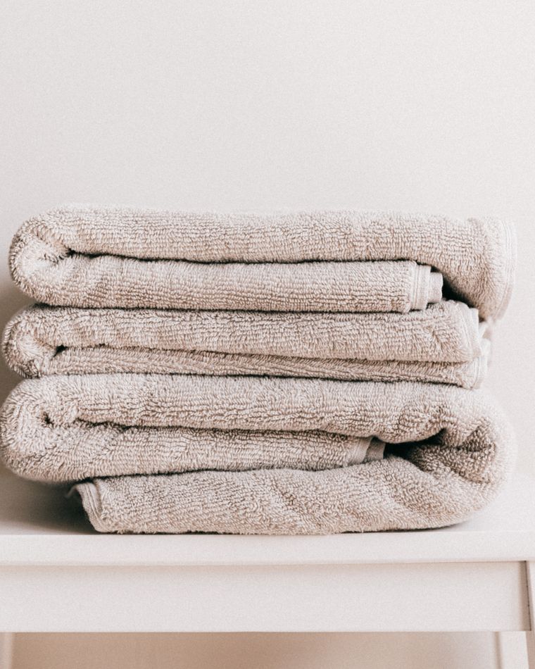 A stack of folded oatmeal towels on a white stool