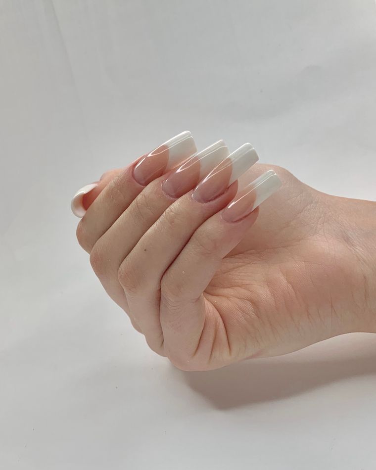 A hand with long milky almond-shaped extensions