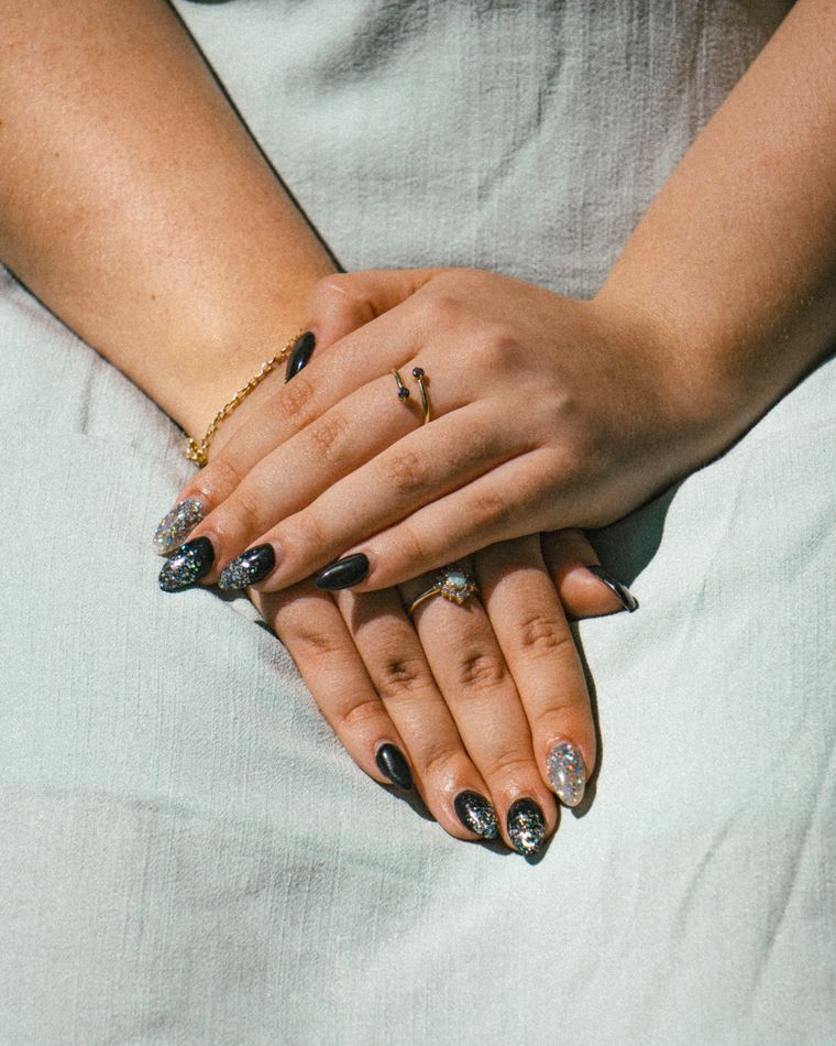 Hands with chrome and onyx nails against a sage linen dress