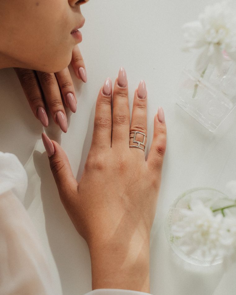 A manicured hand with a solitaire ring resting beside white flowers