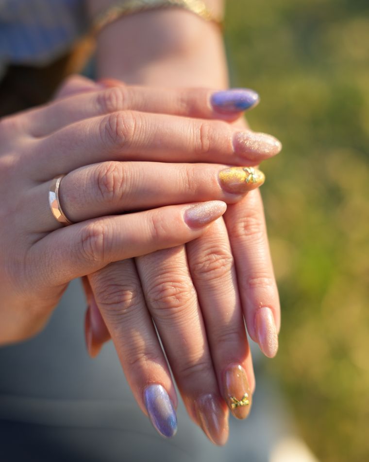 Two hands showing a multicoloured manicure with a different design on each nail
