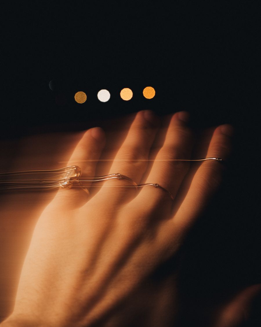 A hand lit warm against a dark background with small golden lights behind.