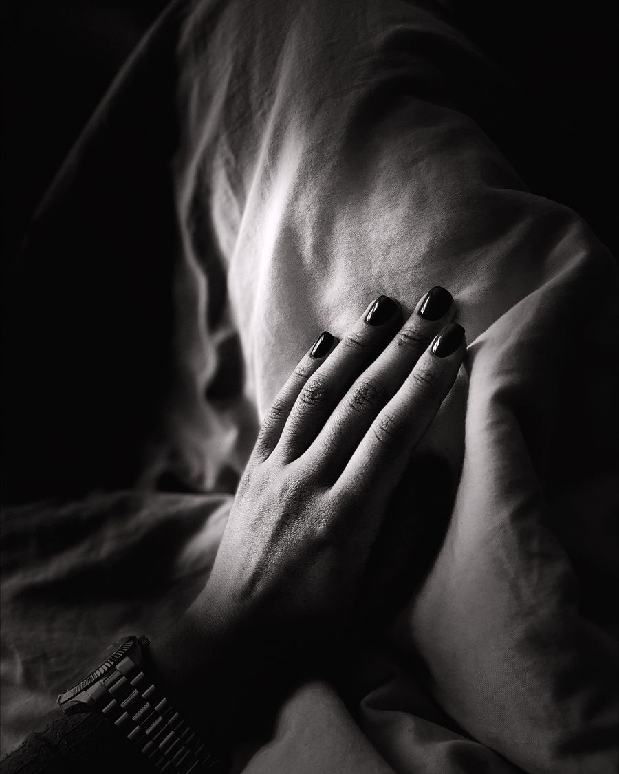 A hand in black and white resting against folded cloth.