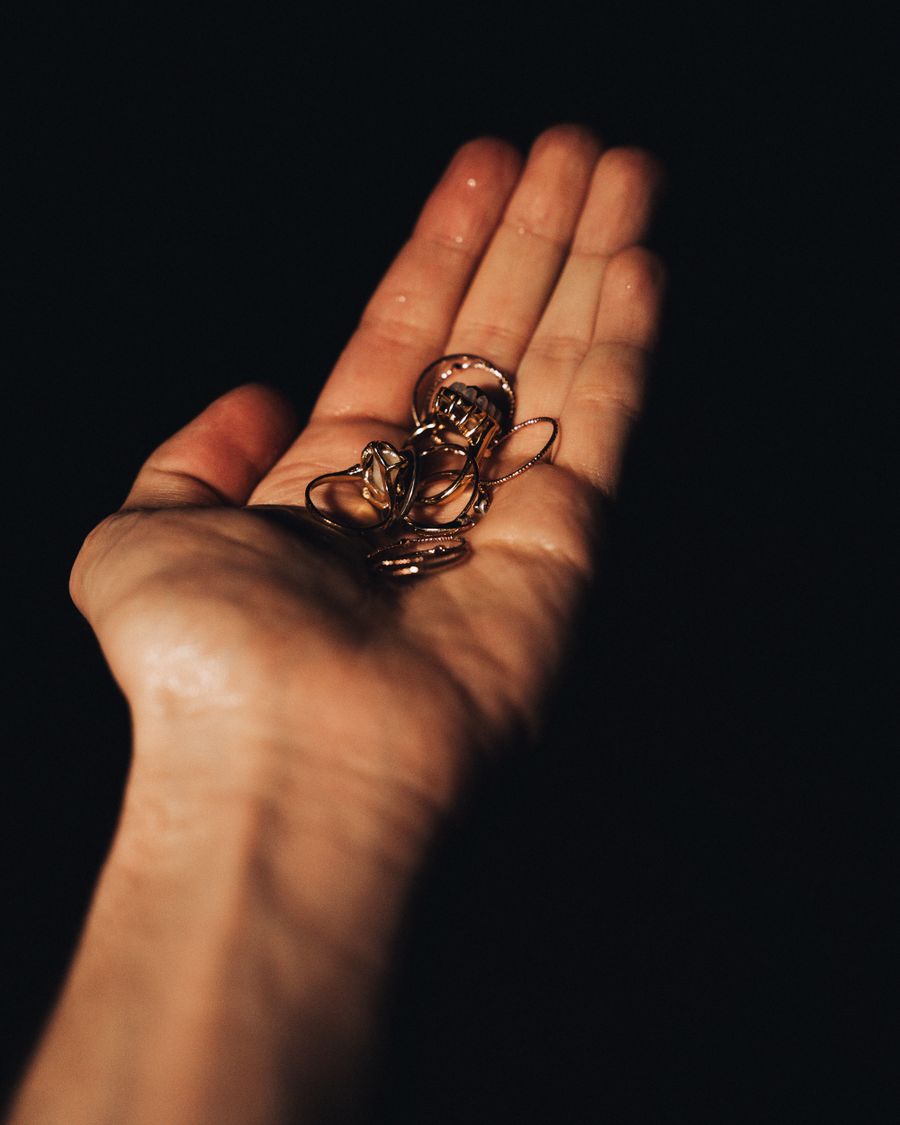 An open palm holding a small gold ornament, lit warm against black.