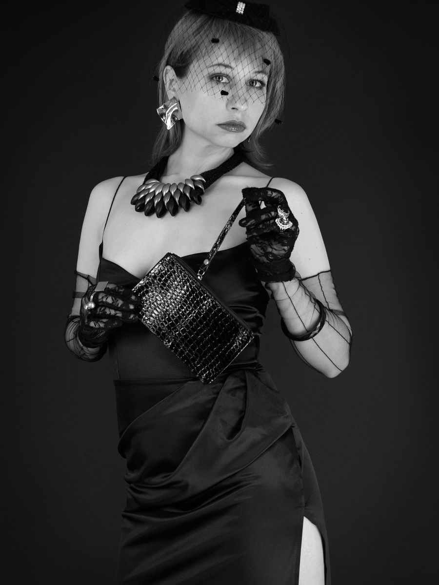 A studio portrait in black and white: a woman in a black gown and long gloves.