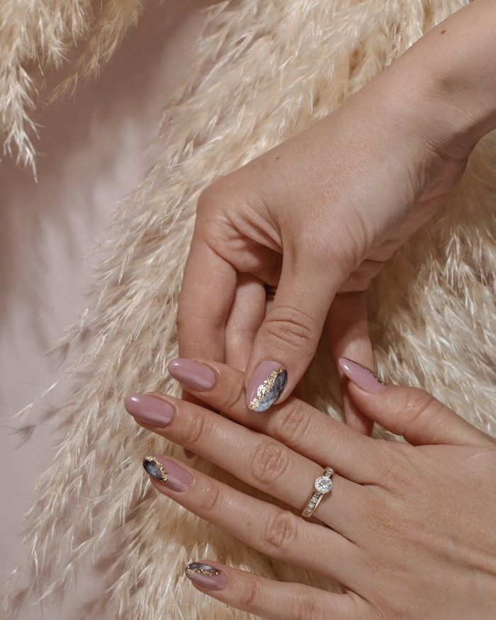 Hands with a soft neutral gel overlay resting on a textured throw
