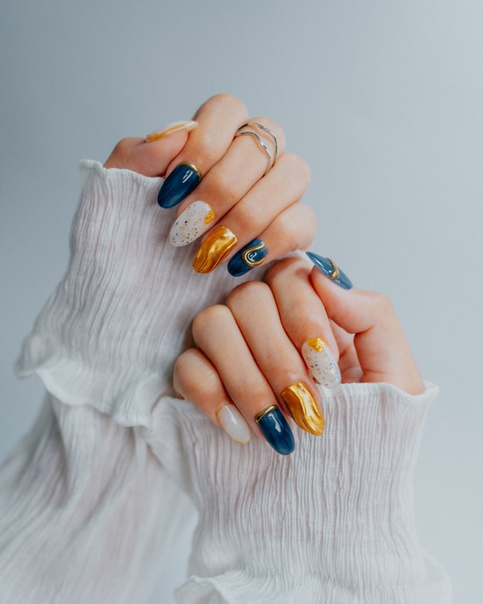 A hand with long polished nails against a pale knitted sleeve