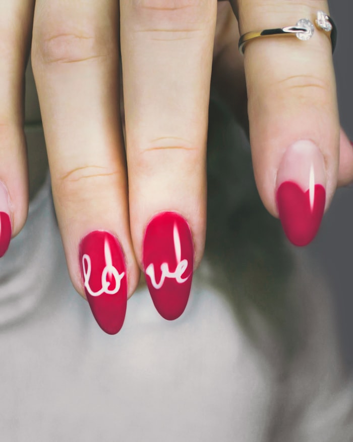 Freehand lettering painted across a set of long nails