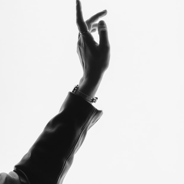 A raised hand in silhouette against a pale wall