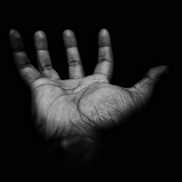 An open palm lit from one side against a black ground
