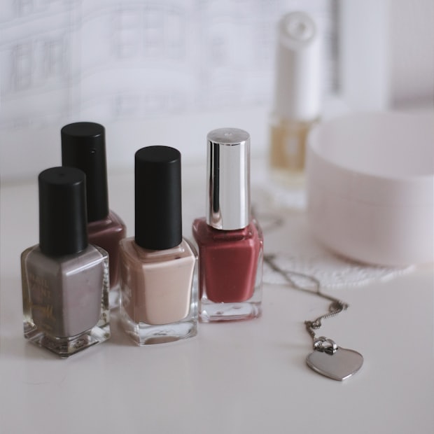 Three bottles of nail polish standing on a pale surface