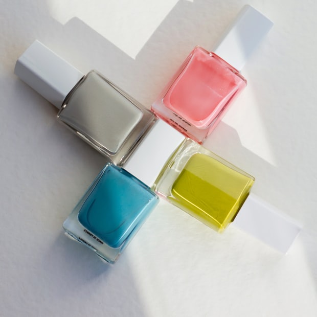 Square polish bottles arranged in a cross on white paper