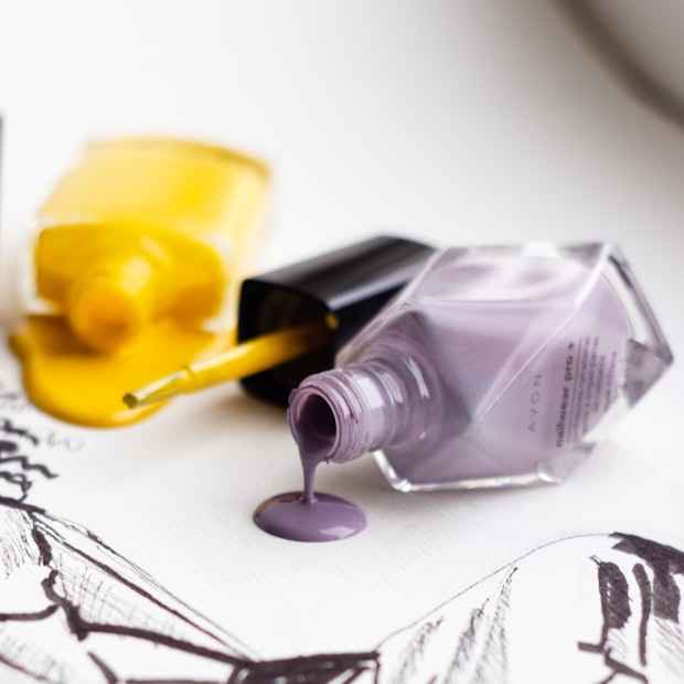 Two open polish bottles spilling onto a light surface