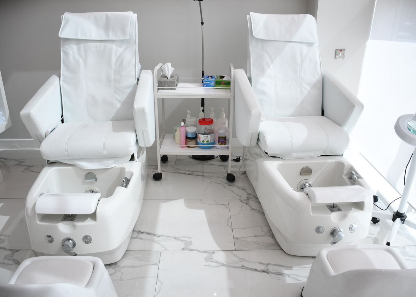 The pedicure room: white spa chairs in a row on a pale marble floor