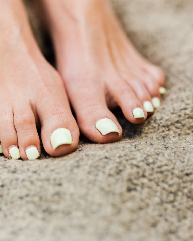 Feet with a fresh cream and mint pedicure on a soft beige blanket