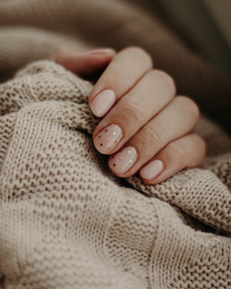 A hand with soft nude nails against an oatmeal knit