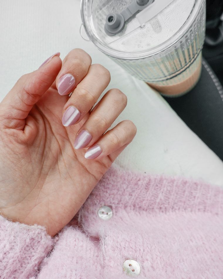 A hand with pale pink nails resting on a blush cardigan