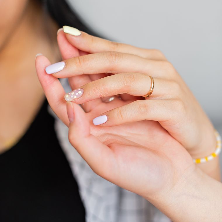 Two hands with ivory-tipped nails and thin gold rings