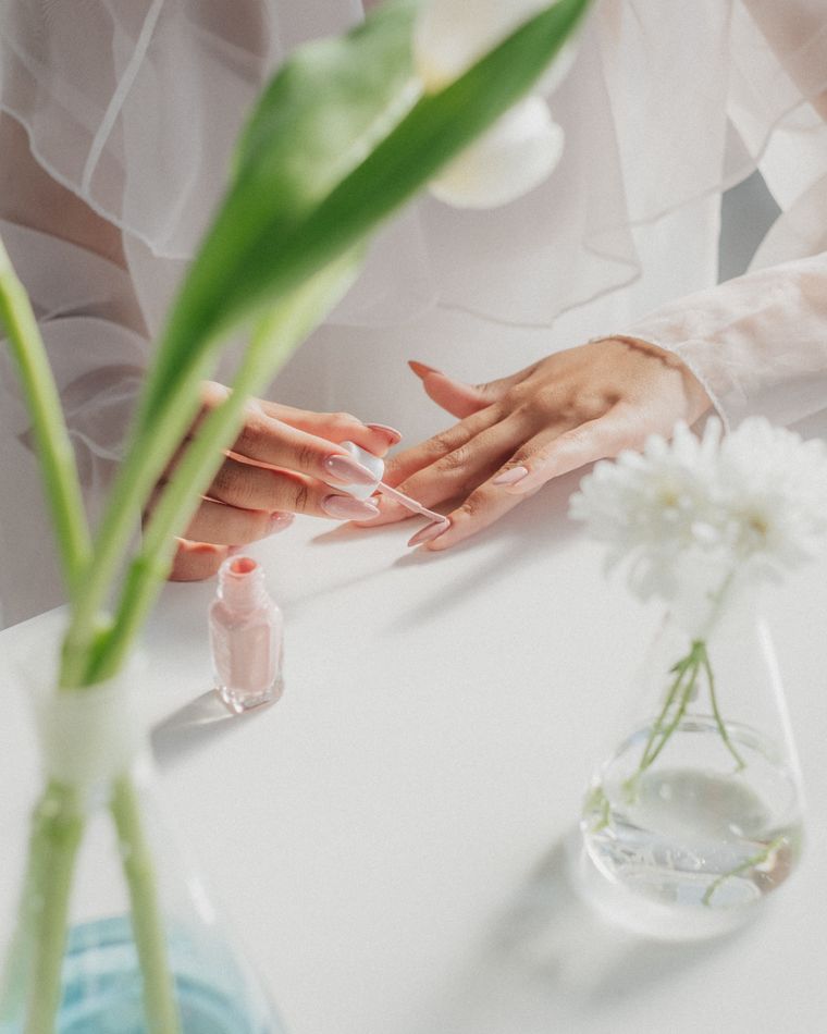 A manicure in progress at a white table beside a vase of white flowers