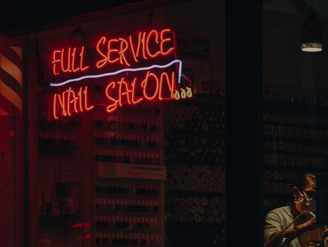 A nail salon shopfront at night under a neon sign