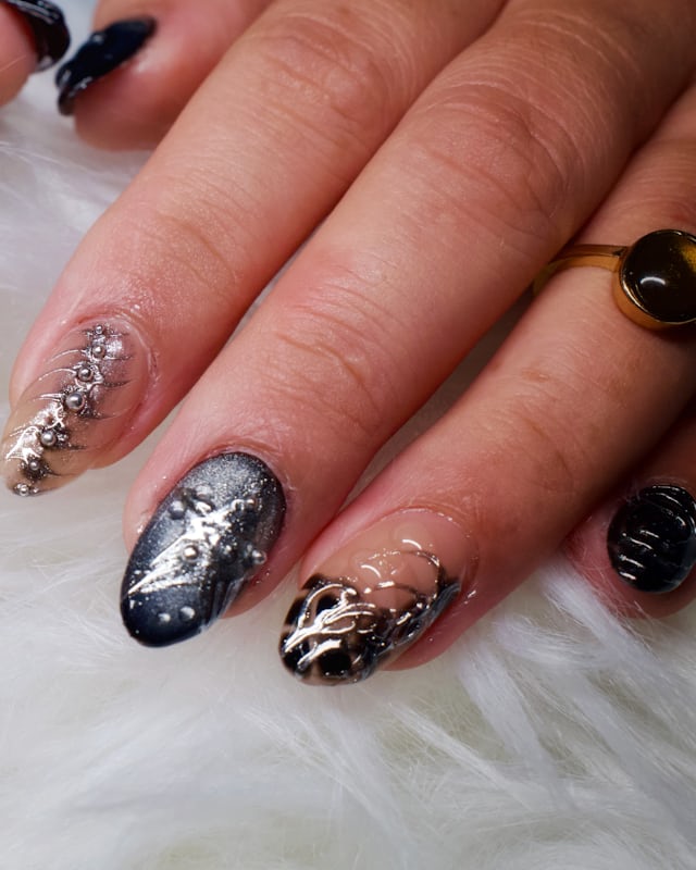 Hands with black and silver marbled nails against a pale fur throw