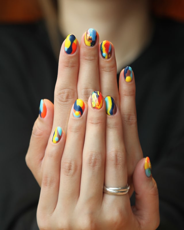 Short nails painted in six different bright colours, one per finger