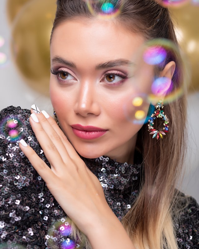 A portrait with silver and blue glitter across the hair and shoulders
