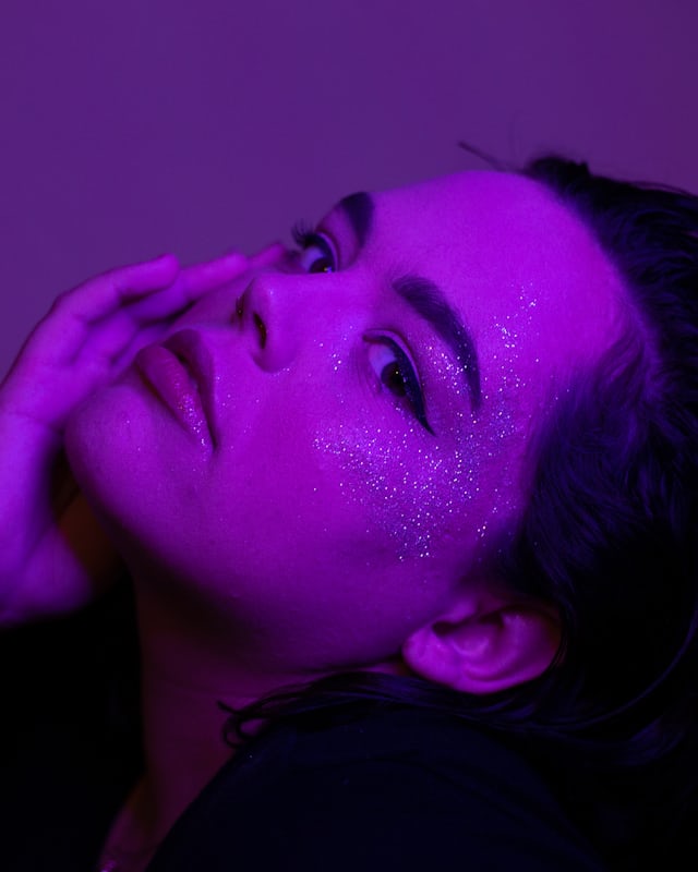 A face lit entirely in deep violet, turned to the light